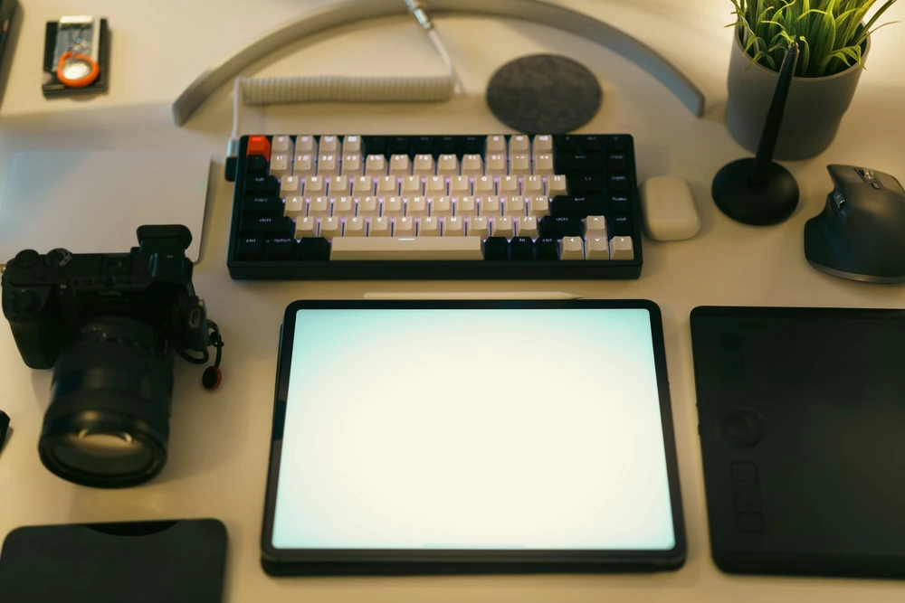 A creative workspace with a computer, graphics tablet and camera.