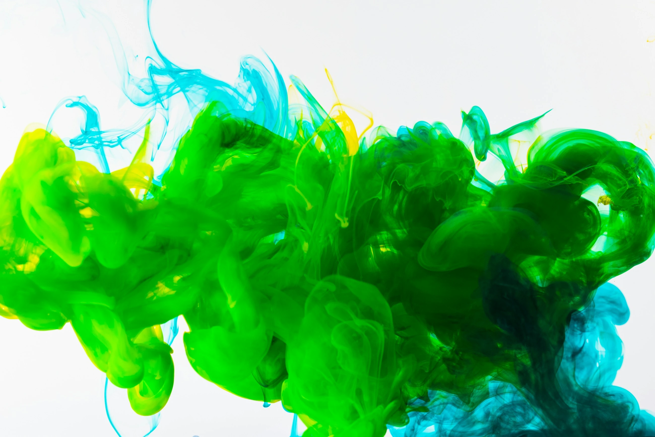 A macro photograph of green and blue ink spreading in water.