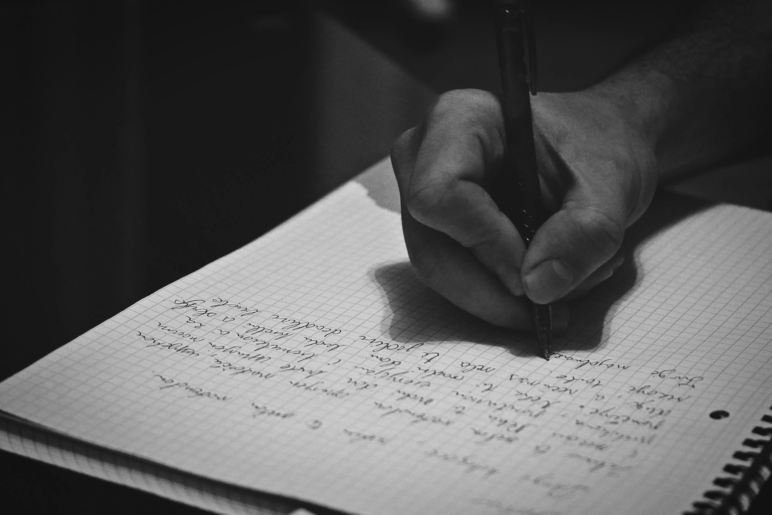 A hand is writing with a pen in a notebook.