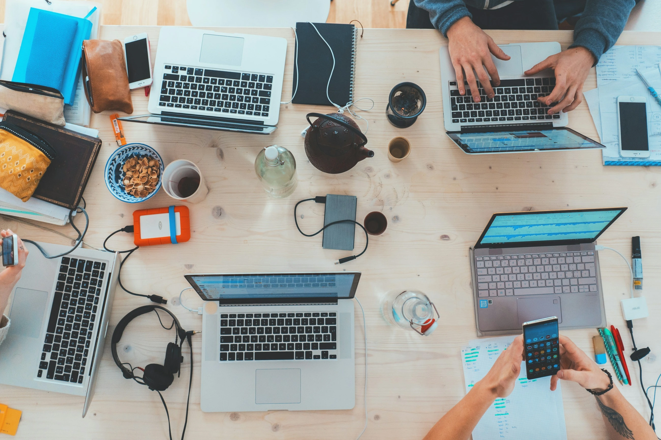 A team is working together at a table with laptops.